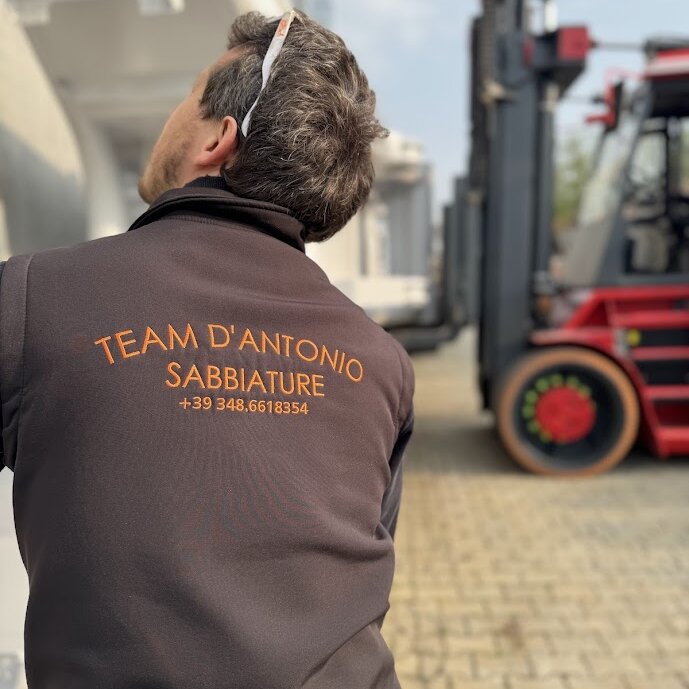 Operaio D'Antonio durante intervento di sabbiatura industriale presso officina con attrezzature per trattamento superfici